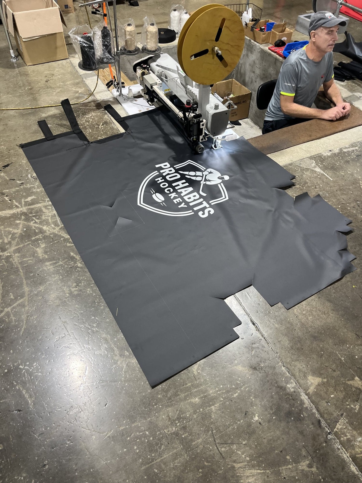 A finished Pro Habits Hockey shooting tarp laid out on the factory floor next to the industrial sewing machine