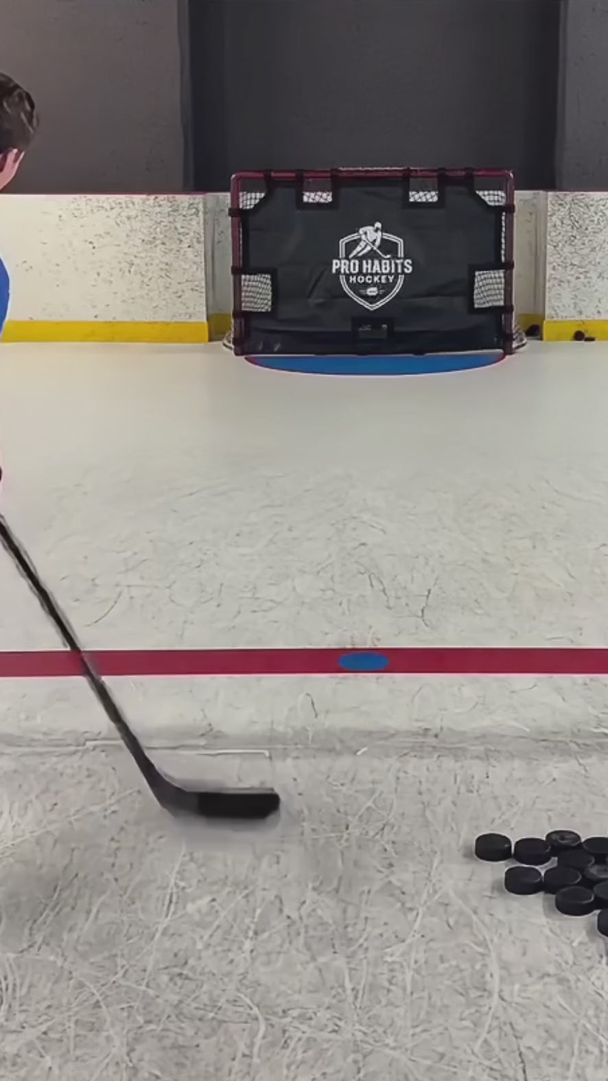 Player shooting pucks at the Pro Habits Hockey shooting tarp on a rink