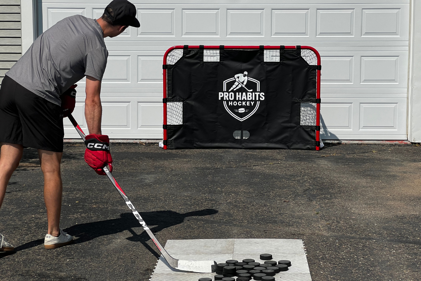 Hockey player practicing with a hockey shooting tarp in a driveway for off-ice hockey training