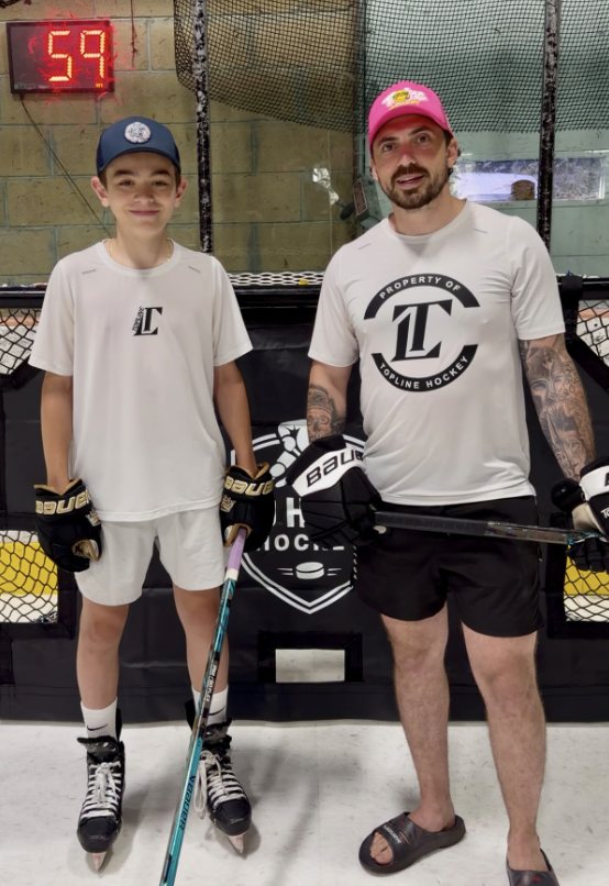Two players posing in front of a Pro Habits Hockey shooting tarp